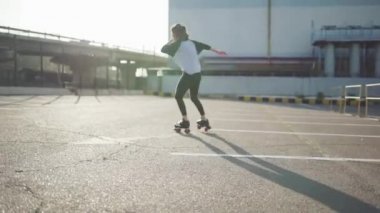 Genç bir kadın paten kayıyor ve sokaklarda dans ediyor.