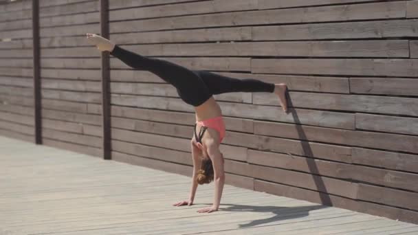 Γυναίκα εξάσκηση γιόγκα θέτει handstand στον τοίχο στο ηλιόλουστη μέρα — Αρχείο Βίντεο