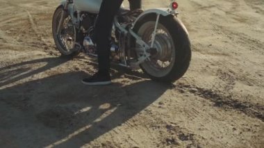 Motosikletli, çölde ağır çekimde lastik patlaması yapıyor.