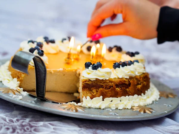 Mujer enciende velas en pastel de cumpleaños —  Fotos de Stock