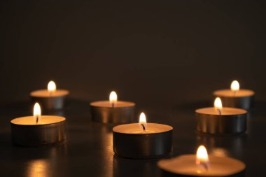 Seven small lighted candles in the dark, selective focus of the candlelight clipart