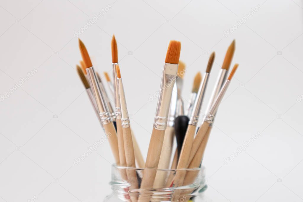 Paint brushes for painting with watercolor and acrylic, in a glass pot, white background