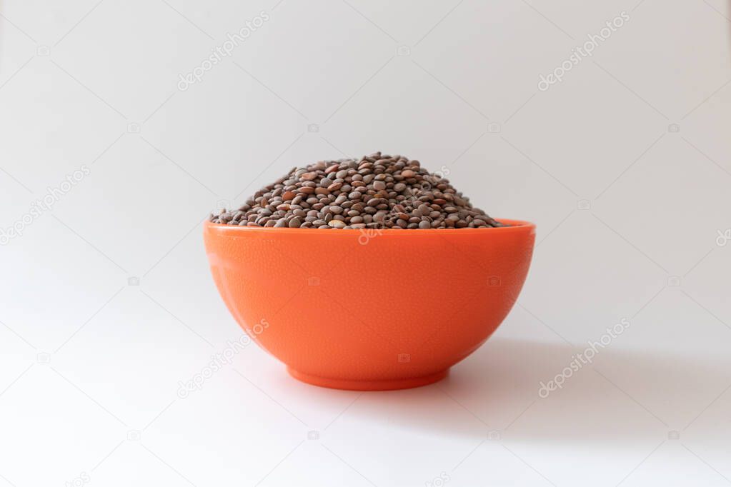 Orange bowl or recipient full of lentils, non perish food, white background