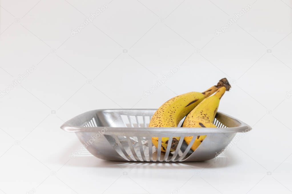 Basket with two bananas in a white background, ready to eat