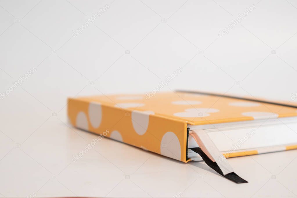 Yellow dotted notebook, with bookmarks (pink, black and white)