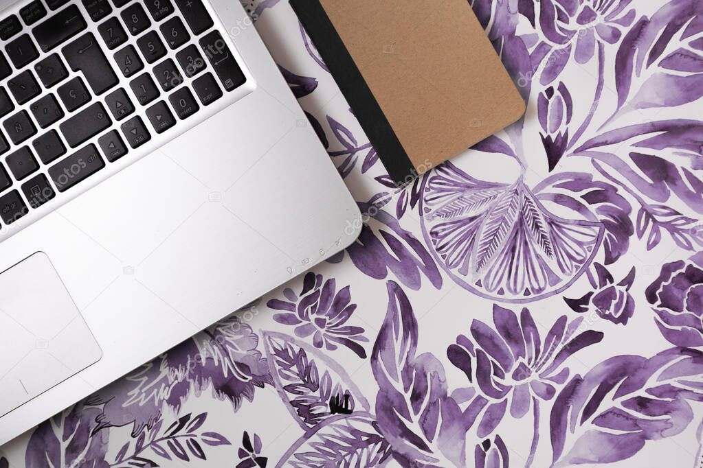 Flat lay of a laptop and a notebook in a flowery purple background, corporate perspective