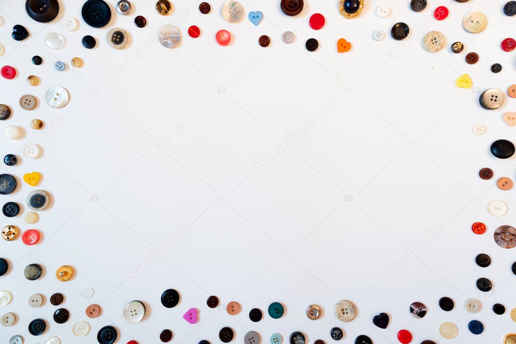 Composition of multiple colorful sewing buttons spreaded in white background. Copy space, flat lay