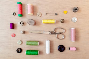 Dikiş malzemelerinin düzlüğü: makas, bobbin, düğmeler, çengelli iğneler, iplikler. Düz yatış, üst görünüm