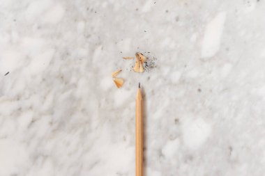 İzole edilmiş kalem daha yeni sivrildi ve mermer zemin, düz zemin ve üst görünüm üzerindeki talaşları...