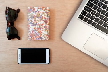 Düz dizüstü bilgisayar, defter, akıllı telefon ve güneş gözlüğü. Ahşap arkaplan, üst manzara