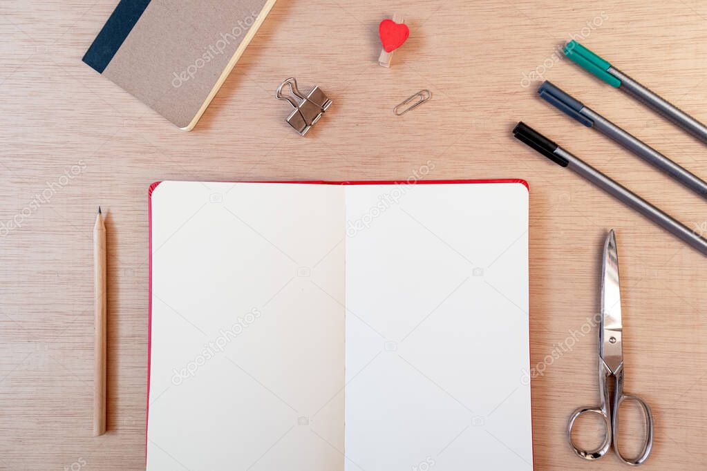 Blank open notebook with office supplies: scissors, pencils, pens and clips. Flat lay, top view