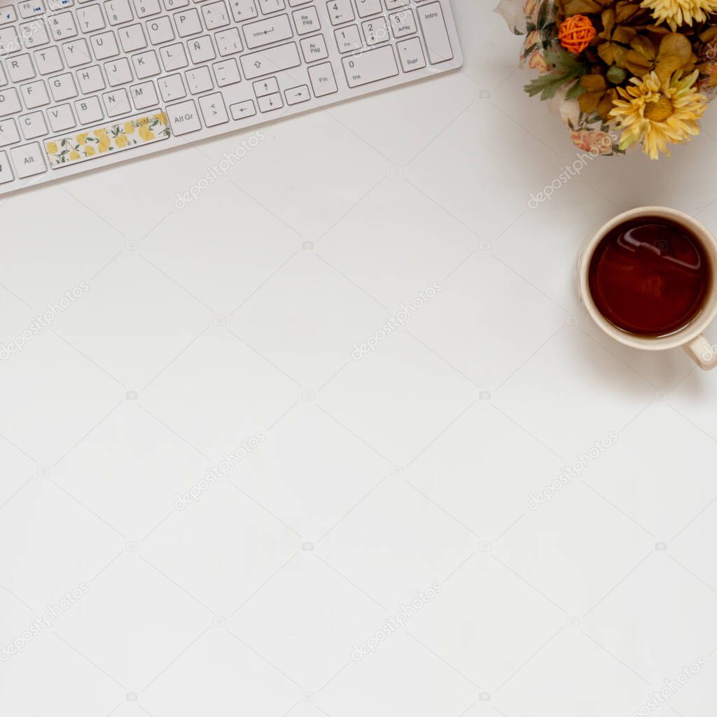 Square Flat Lay of an office: laptop keyboard, coffee and plants. With copy space white background