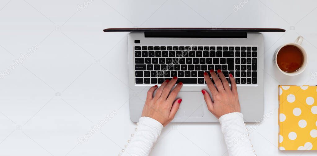Female hands typing on keyboard laptop while telecommuting, banner with copy space, for bloggers, business. Top view, flat lay