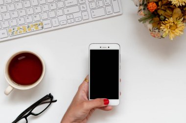 Ofiste evden işe giderken beyaz akıllı telefonu tutan bir kız. Düz açı, üst görünüm