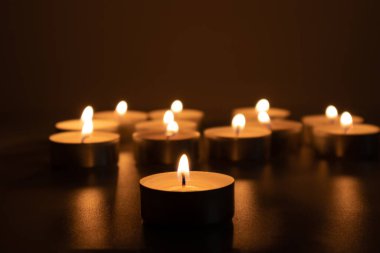 Little candles poorly lit in the darkness. Scene of sorrow and sadness clipart