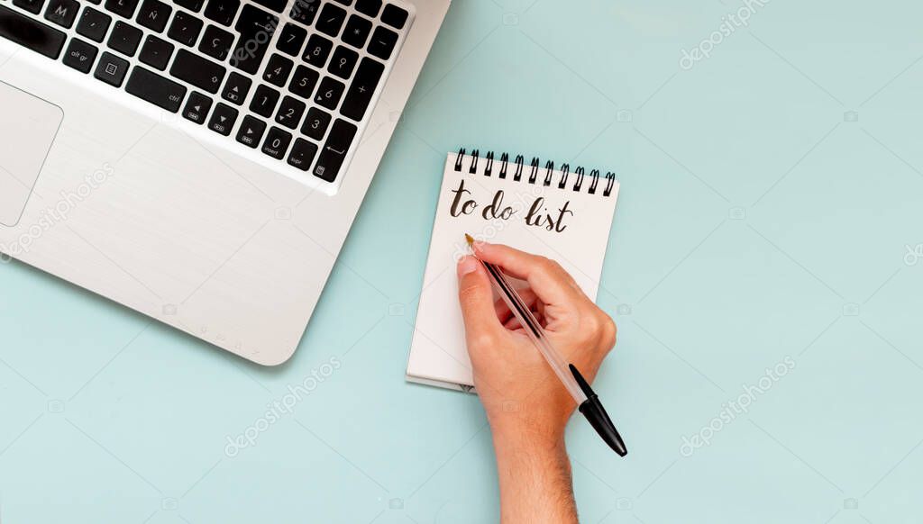 Man writing in to do list in the office, flat lay, workspace of busy entrepreneur businessman