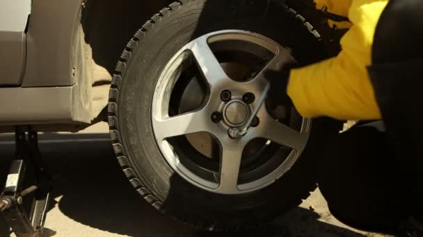 Nő cserél autó kerék: csavarozás csavarkulccsal elölnézetből — Stock videók
