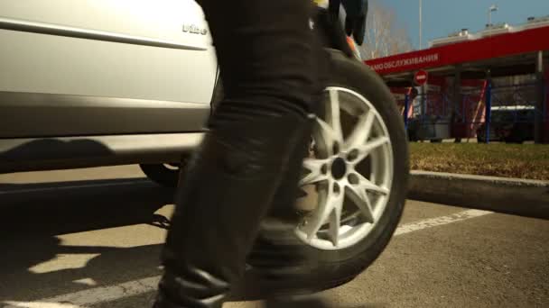 Kvinnan rullar bilhjul och placerar framhjulet på plats — Stockvideo
