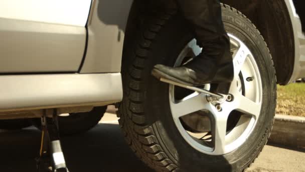 Nő cserél autó kerék: csavarozás csavarkulccsal kemény segítségével lábak — Stock videók