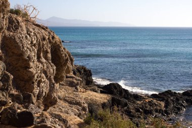 Costa Calma Beach siyah kayalar. Mavi kıyı şeridi. Playa Barca, Fuerteventura, Kanarya Adaları, İspanya. Istmo de la pared görünümü