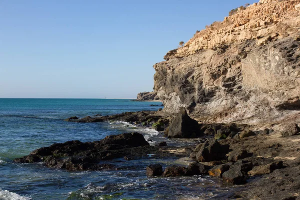 Черные скалы пляжа Коста-Калма. Голубое побережье. Playa Barca, Fuerteventura, Канарские острова, Испания. Istmo de la converted view — стоковое фото