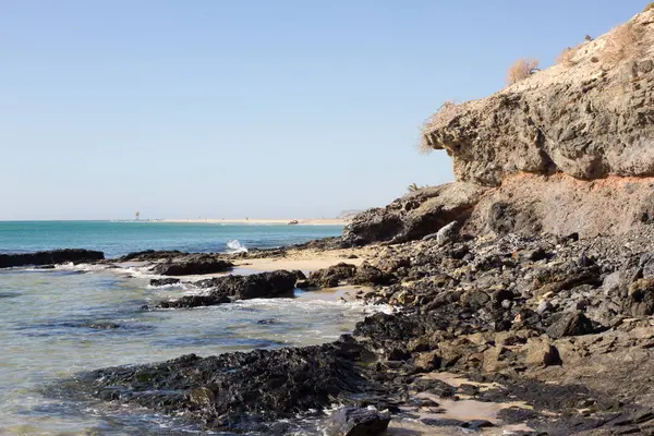 Черные скалы пляжа Коста-Калма. Голубое побережье. Playa Barca, Fuerteventura, Канарские острова, Испания. Istmo de la converted view — стоковое фото