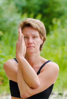 Hatha yoga. Oturmuş yarım lotus, Yoga poses, asan. Sağlıklı yaşam ve doğal kavramı. Pratik yoga, oturma ve namaste, giyiyor spor giyim, sütyen, park, açık kat kişinin elinde