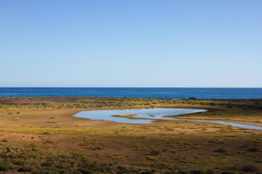 Panoramik okyanus manzaralı. Volkan, siyah kayalar. Göl.