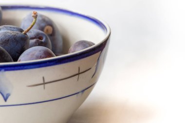 Mavi Erik beyaz masaya bir tabak içinde. İzole meyve.