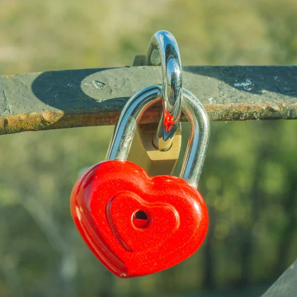 Κόκκινη καρδιά πάνω από ανοιχτόχρωμο φόντο. Εξασφαλίστε στην καρδιά του σχήματος στη γέφυρα των εραστών. Ημέρα του Αγίου Βαλεντίνου καρτ ποστάλ. Κλειστό λουκέτο — Φωτογραφία Αρχείου