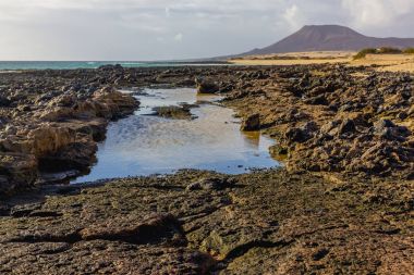 Lav alanları. Siyah mineraller. Kõyõ alanlarõ arazi ve su Fuerteventura ve Atlas Okyanusu arasında. İspanya, Europe.