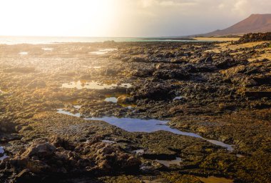Lav alanları. Siyah mineraller. Kõyõ alanlarõ arazi ve su Fuerteventura ve Atlas Okyanusu arasında. İspanya, Europe.