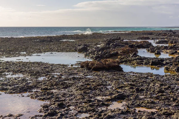 Лавовые поля. Черные минералы. Прибрежная зона между сушей и водой в Фуэртевентуре и Атлантическом океане. Испания, Европа . — стоковое фото