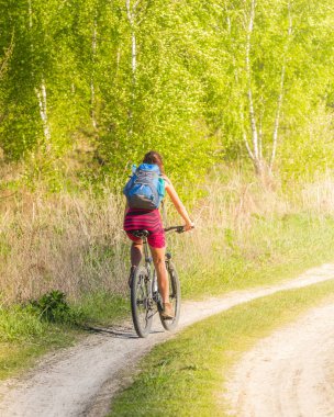 Güzel kız vahşi doğada toprak yolda Bisiklete binme. Kız Bisiklete binme bisiklet. Kız bisiklet ile gidiyor.