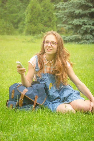 Adolescente sentada de pernas cruzadas ao ar livre na grama de verão verde — Fotografia de Stock
