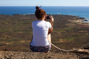 Kayanın üzerinde bir deniz üzerinde oturan genç kız.