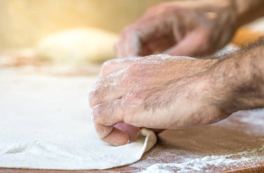 Erkek eller evde mutfaktaki masada hamur yapıyor.