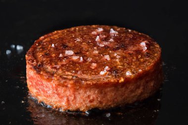 Bitki bazlı vejetaryen burger köftesi ve kaya tuzu pişiriliyor. 