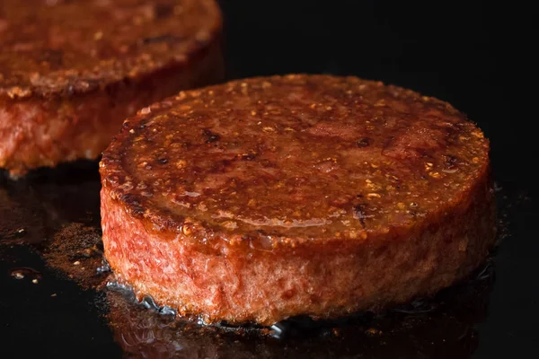 Hambúrgueres vegetarianos à base de plantas sendo cozidos em preto liso — Fotografia de Stock