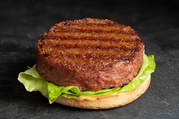 Freshly grilled plant based burger patty on bun with lettuce and — Stock Photo, Image