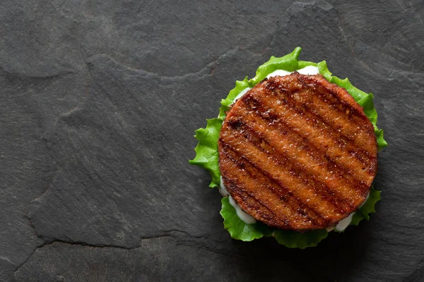 Świeżo grillowane patty na bazie hamburgerów na bułce z sałatą i — Zdjęcie stockowe