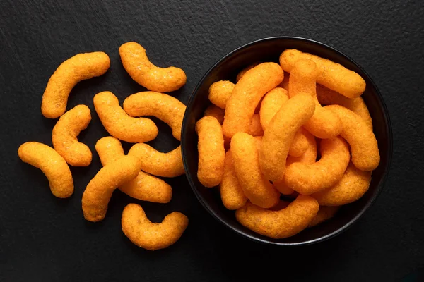 Geëxtrudeerde kaasbolletjes in een zwarte keramische kom naast gemorste l — Stockfoto