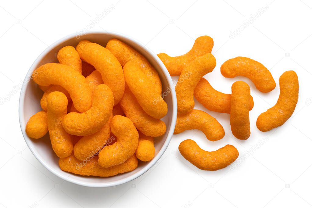 Extruded cheese puffs in a white ceramic bowl next to spilled ch