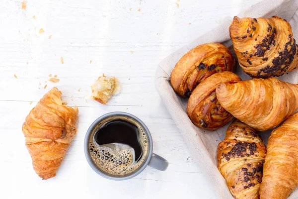 Continental breakfast with black coffee and basket of pastries. — Stock Photo, Image