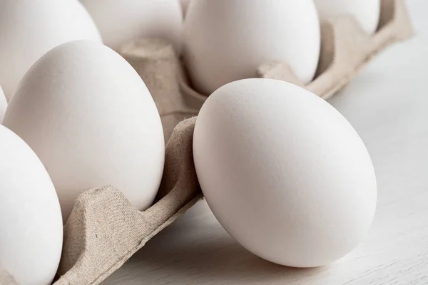 Całe jajko obok tacy z jajkami. — Zdjęcie stockowe