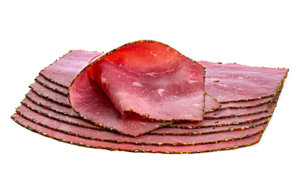 A folded slice of pastrami on top of arranged slices of pastrami isolated on white.