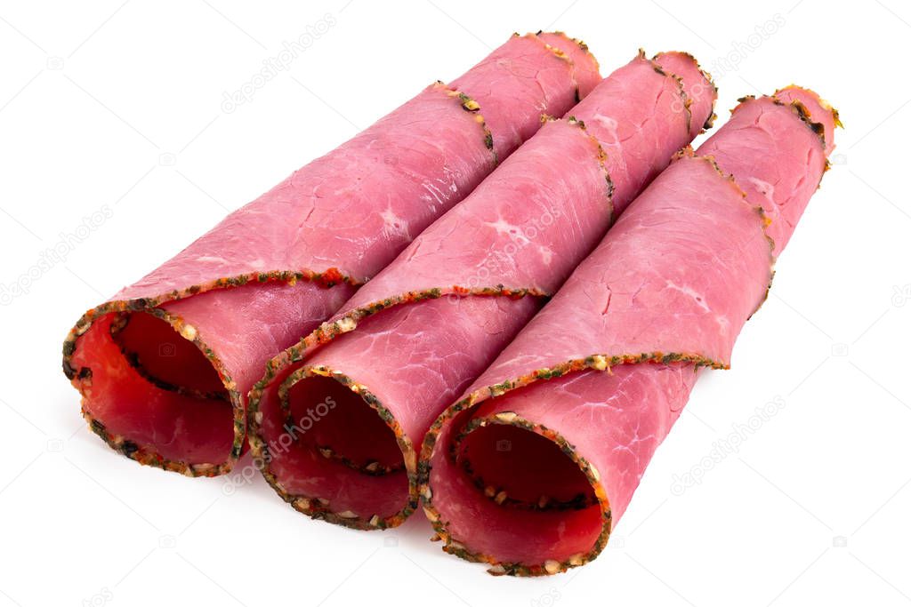 Three rolled up slices of pastrami isolated on white.