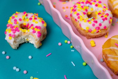 Renkli bir arka planda pembe servis tepsisine serpiştirilmiş mini çörekler.