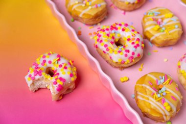 Renkli bir arka planda pembe servis tepsisine serpiştirilmiş mini çörekler.