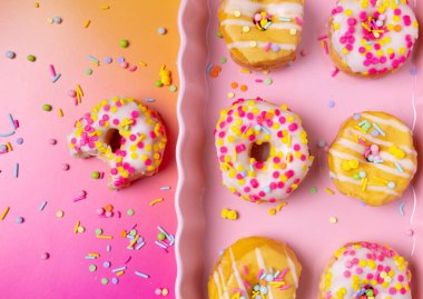 Renkli bir arka planda pembe servis tepsisine serpiştirilmiş mini çörekler.